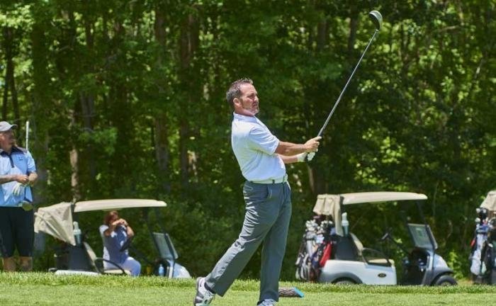 male golfer swinging golf club on course