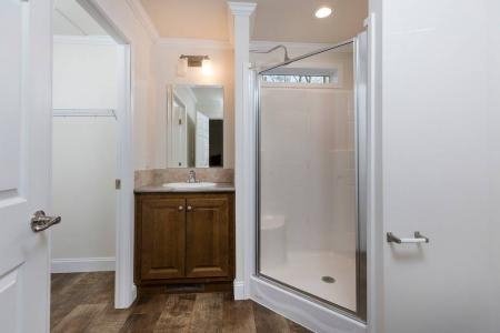 white bathroom with walk-in shower brown vanity and closet